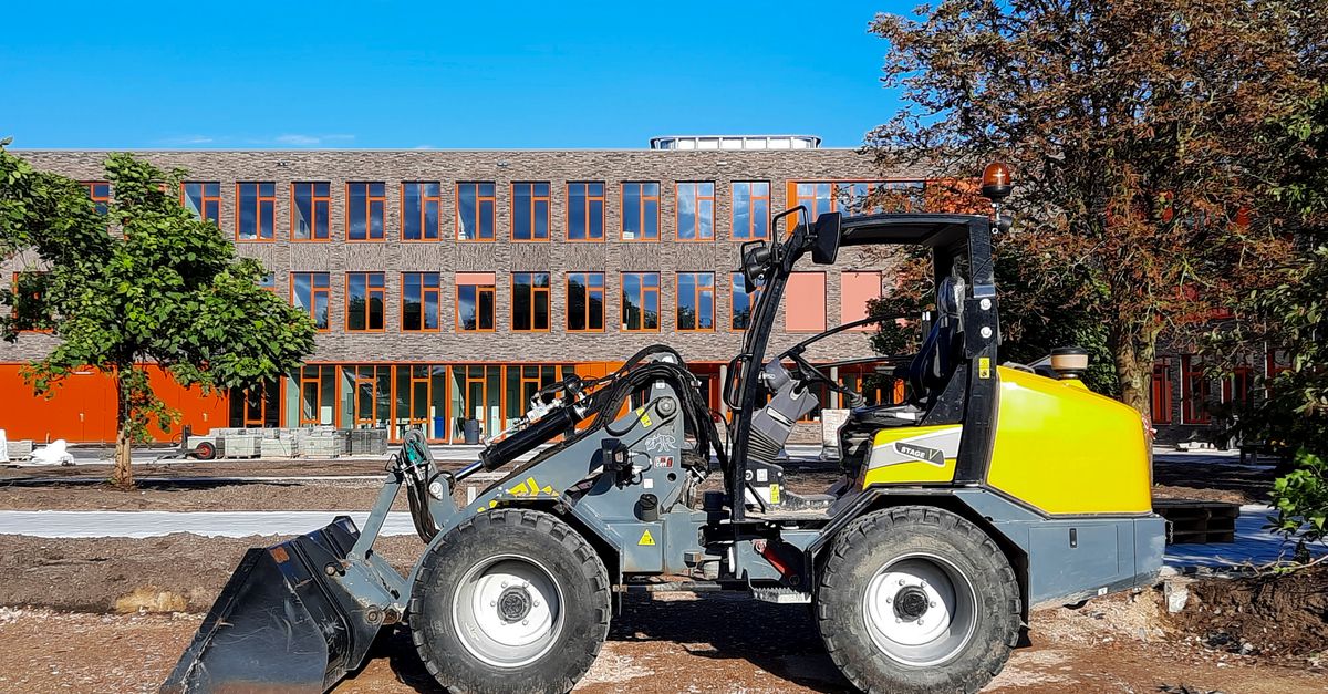 Yellow loader machine at a construction site with modern building background.
