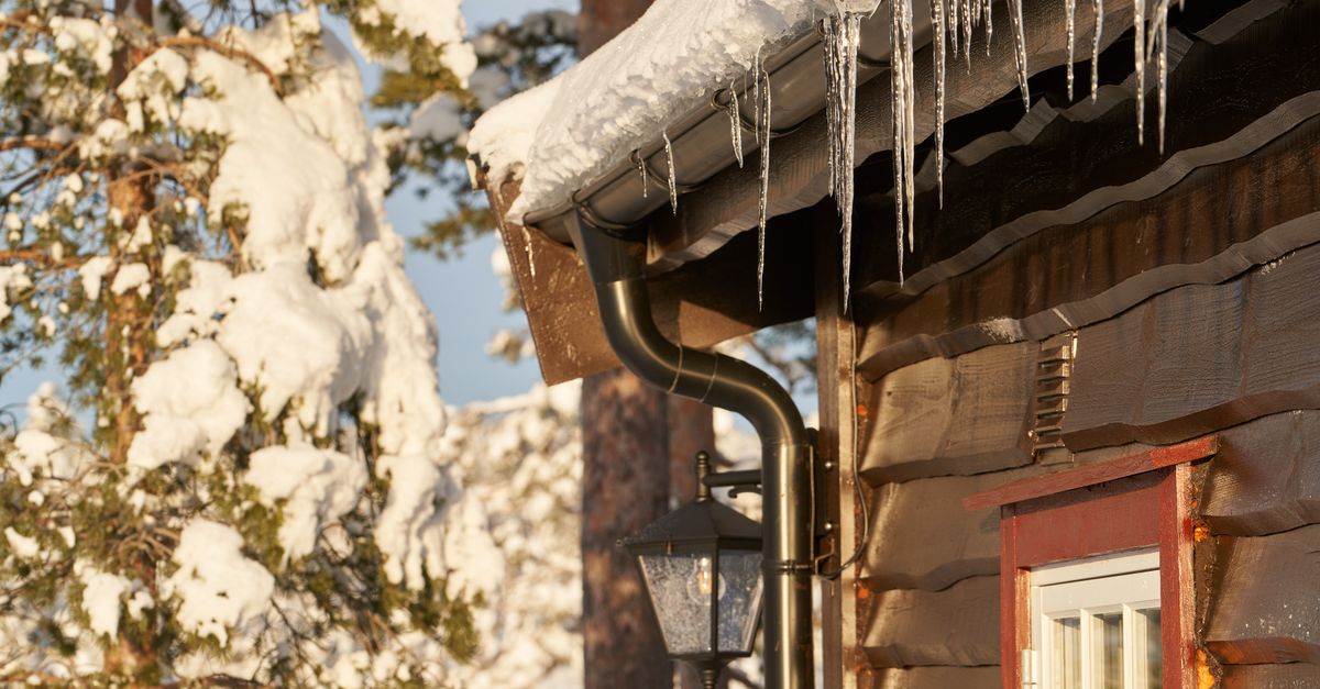 Cozy wooden cabin with icicles on the roof, set in a snowy forest.