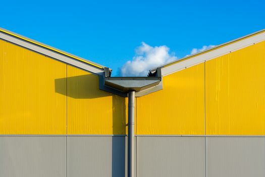 Close-up of a vibrant yellow industrial building exterior against a clear blue sky.