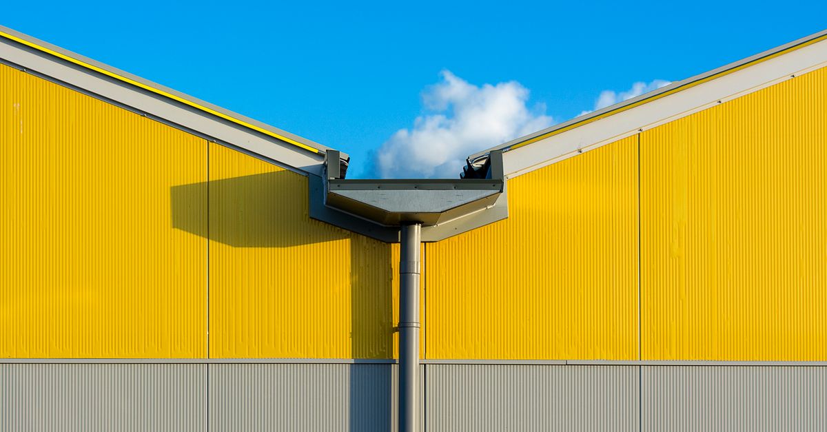 Close-up of a vibrant yellow industrial building exterior against a clear blue sky.