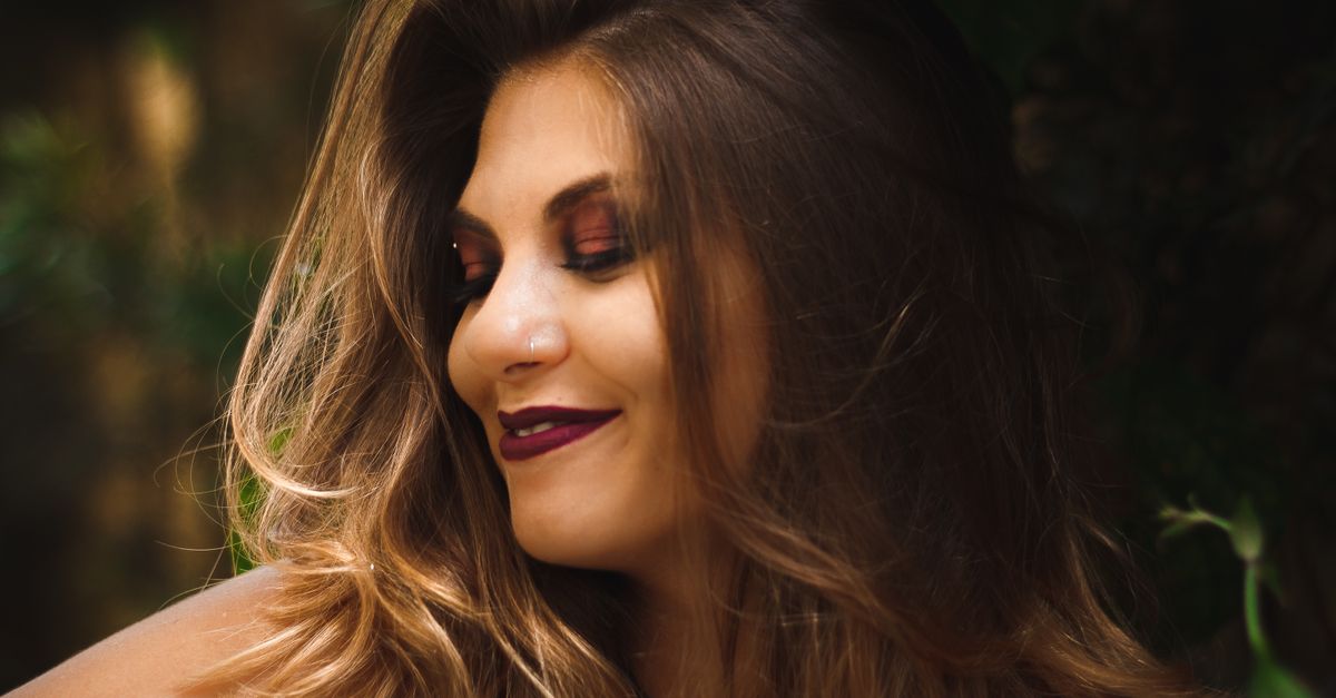 A captivating outdoor portrait of a smiling woman with vibrant makeup, perfect for fashion and lifestyle themes.
