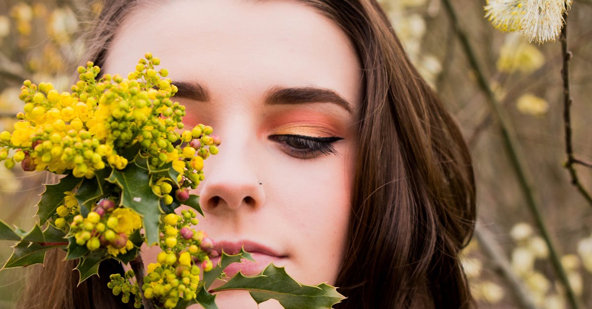 Close-up portrait of a woman with bright eye makeup surrounded by spring flowers.