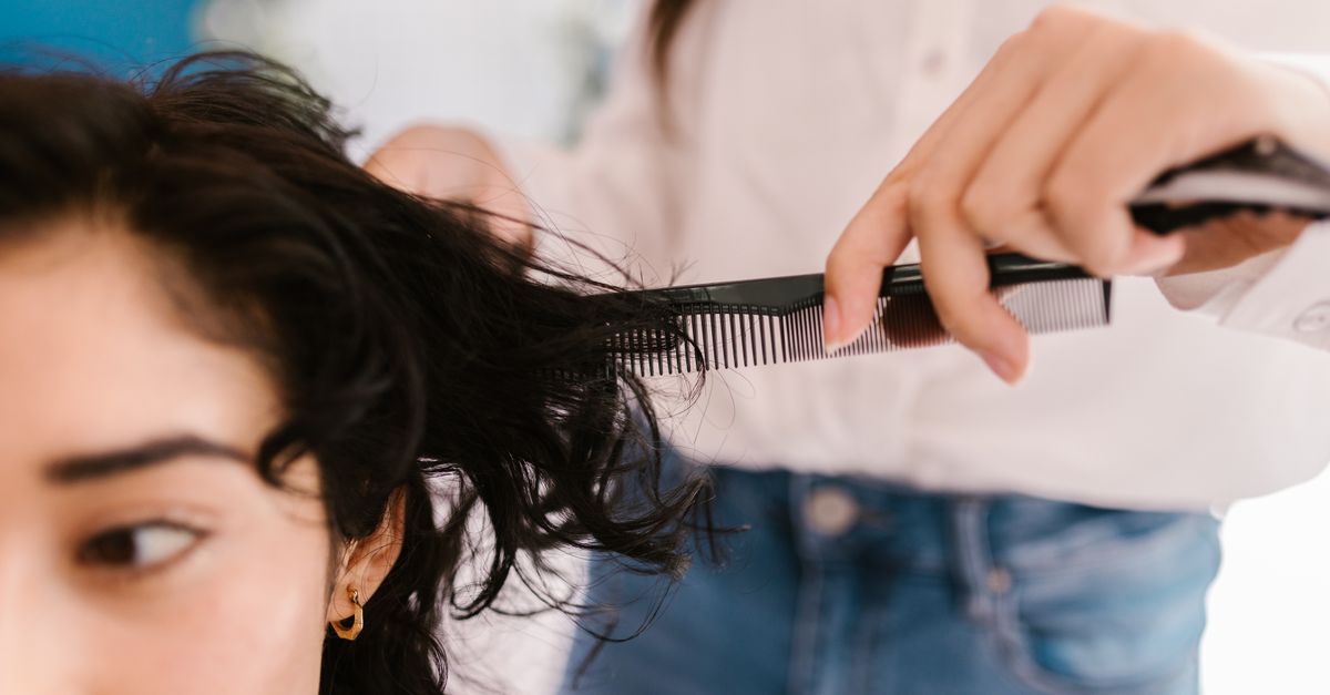 Close-up of hairstylist cutting client's hair in a salon setting.