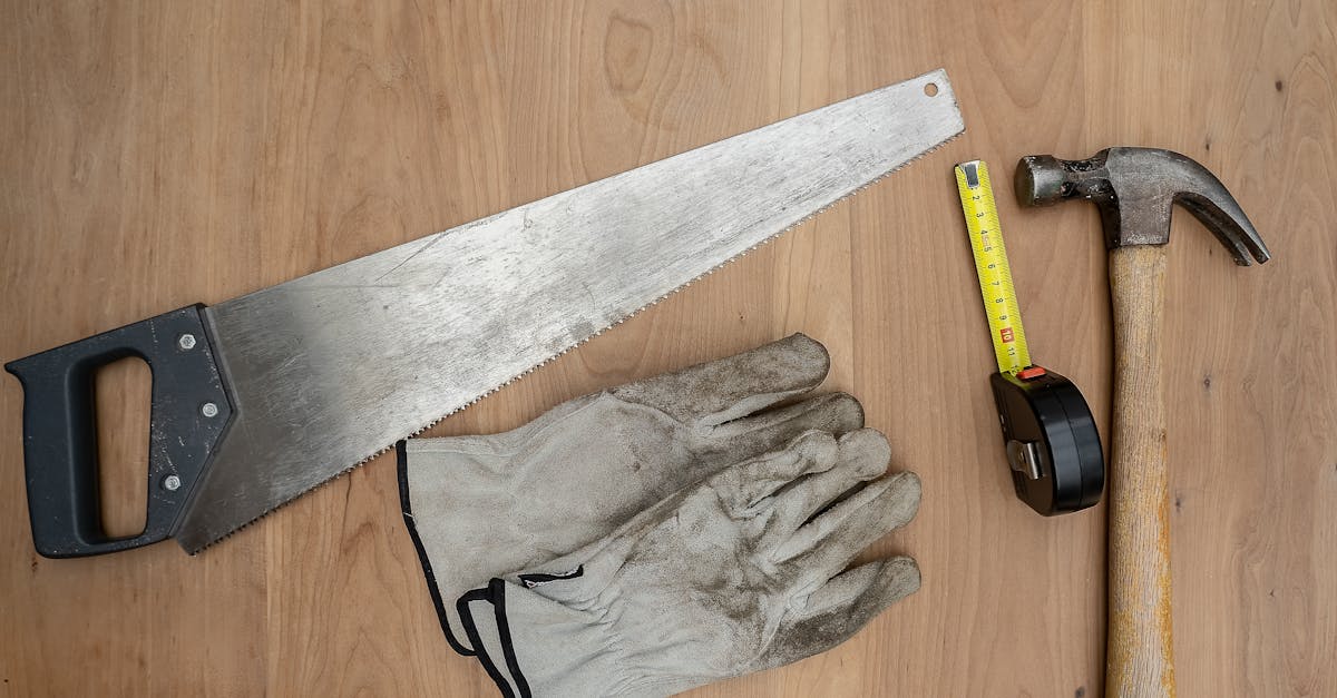 Flat lay of essential carpentry tools including a saw, hammer, and tape measure on wooden surface.