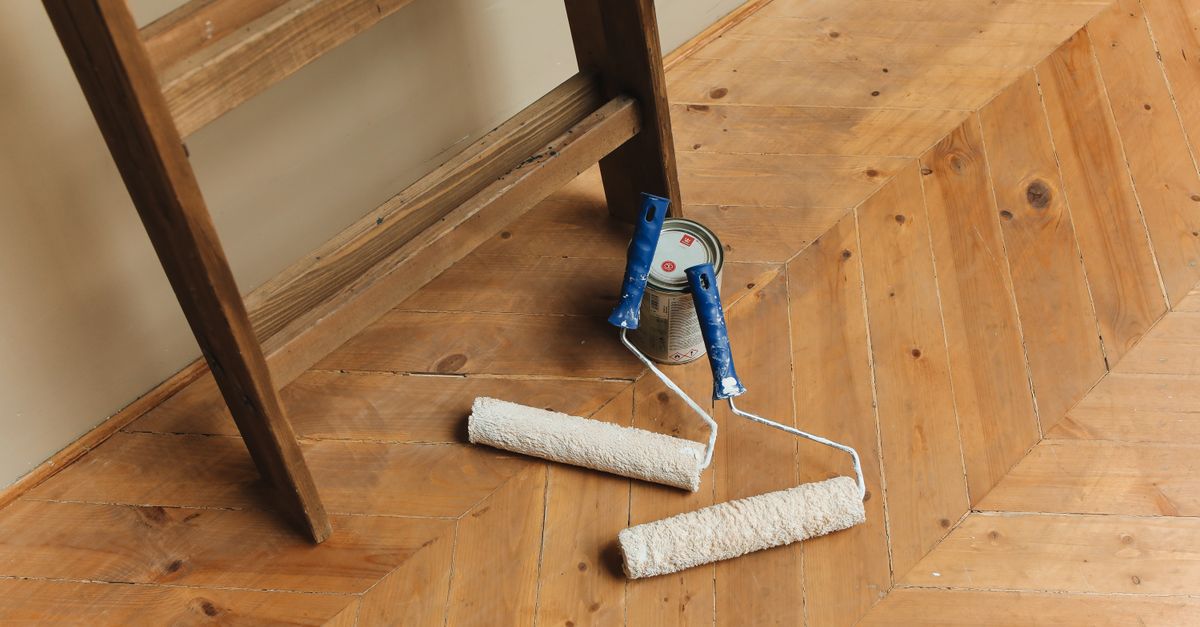 Paint rollers and ladder on a wooden floor, perfect for DIY renovation projects.