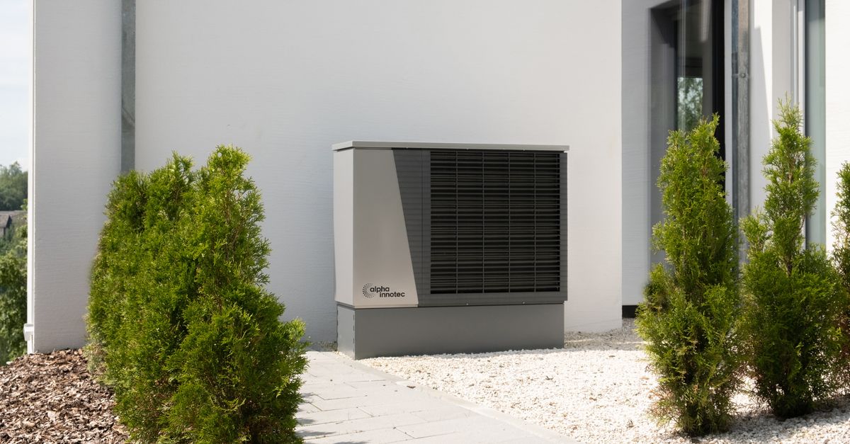 Outdoor air conditioner unit on a modern building surrounded by greenery and landscaping.