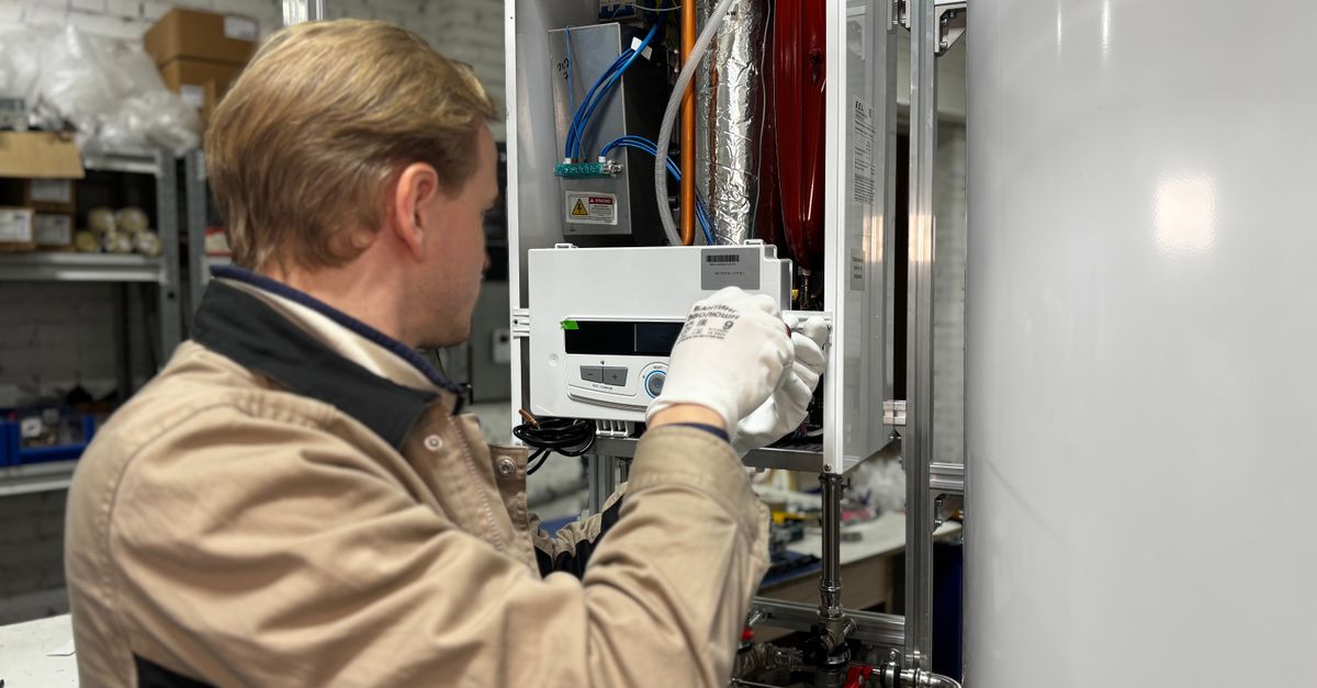 Technician installing or repairing a heating system in an indoor workshop setting.
