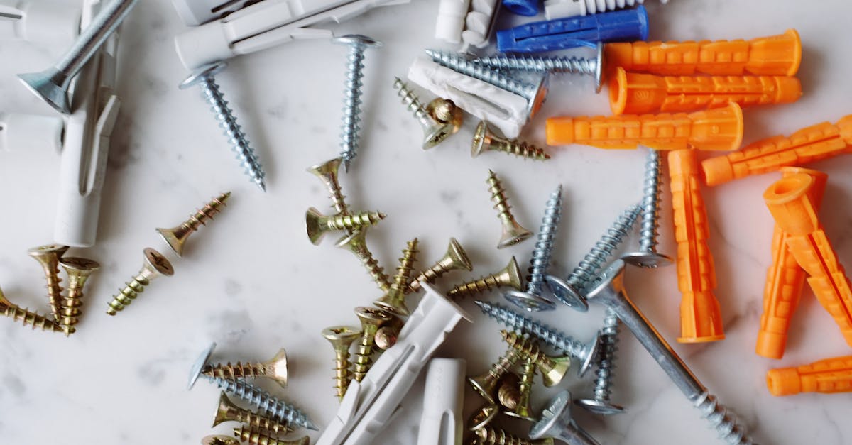 Set of various multicolored plastic dowels with metal screws of different sizes placed on white marble table in modern workshop