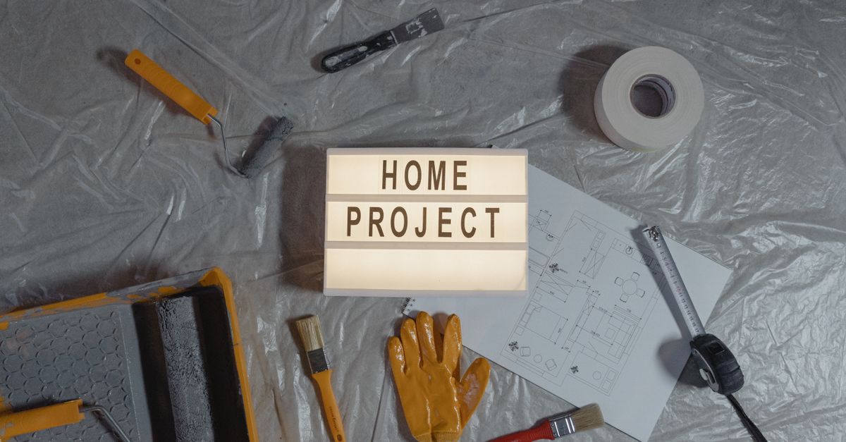 Flat lay of home improvement setup with tools, gloves, and floor plan for DIY projects.