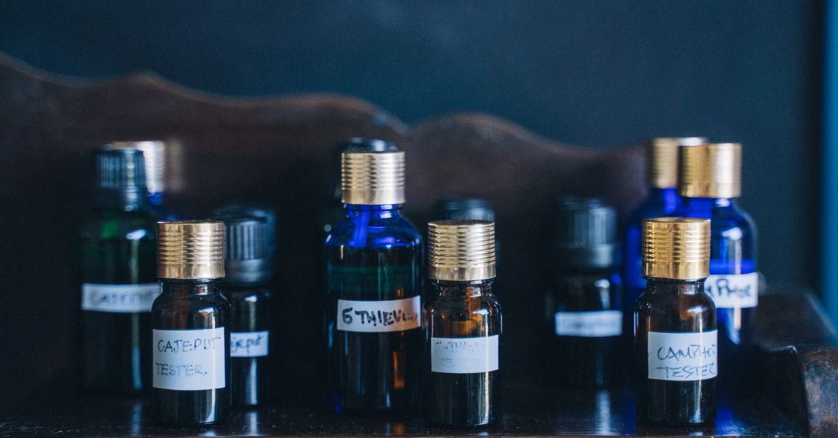 Close-up of glass bottles with essential oils arranged on a wooden shelf, labeled with various oils.