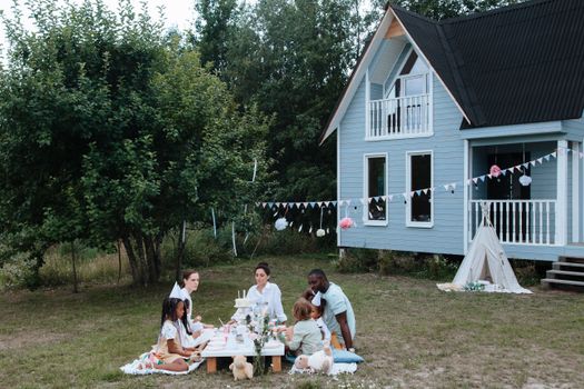 A diverse group enjoying a garden party around a table outdoors.