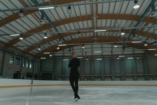 A figure skater gracefully performs on an indoor ice rink, showcasing skill and elegance.