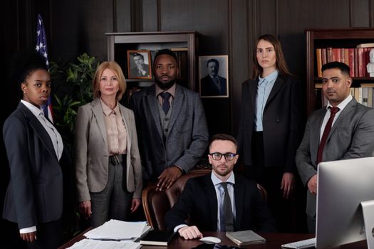 A diverse group of business professionals posing in an office, showcasing teamwork and leadership.