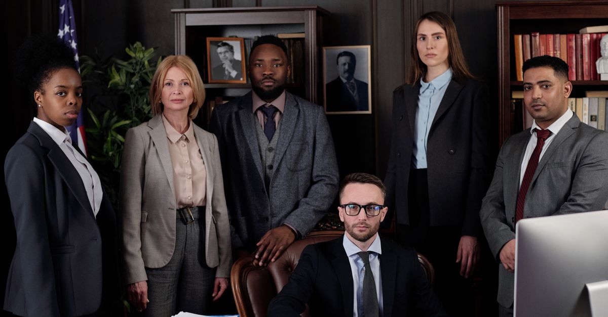 A diverse group of business professionals posing in an office, showcasing teamwork and leadership.