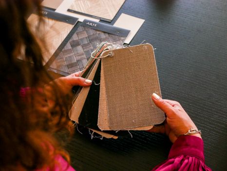 Designer examining fabric swatches for interior design on a black table.