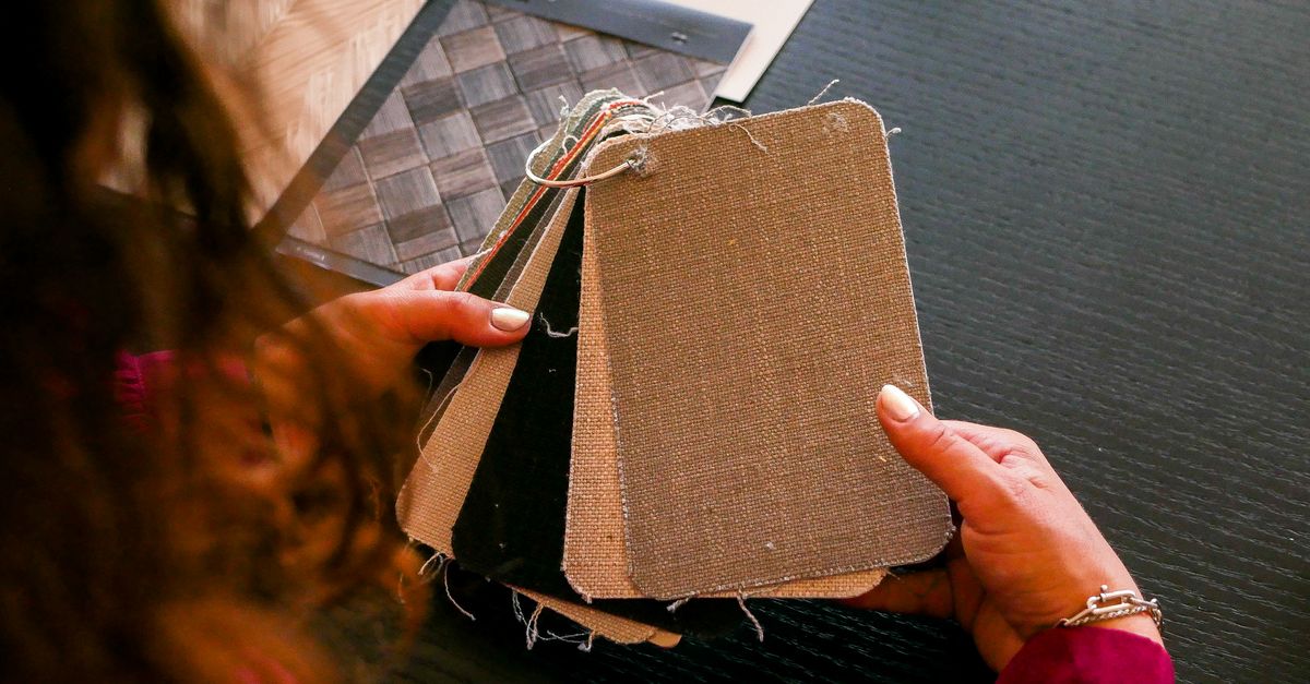 Designer examining fabric swatches for interior design on a black table.