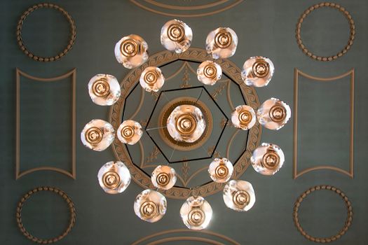 A top-down view of an intricate chandelier and ornate ceiling design, showcasing classic elegance.