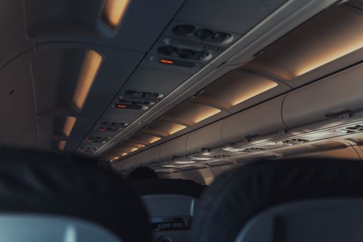 Interior view of a commercial airplane cabin focusing on overhead lights and seats.