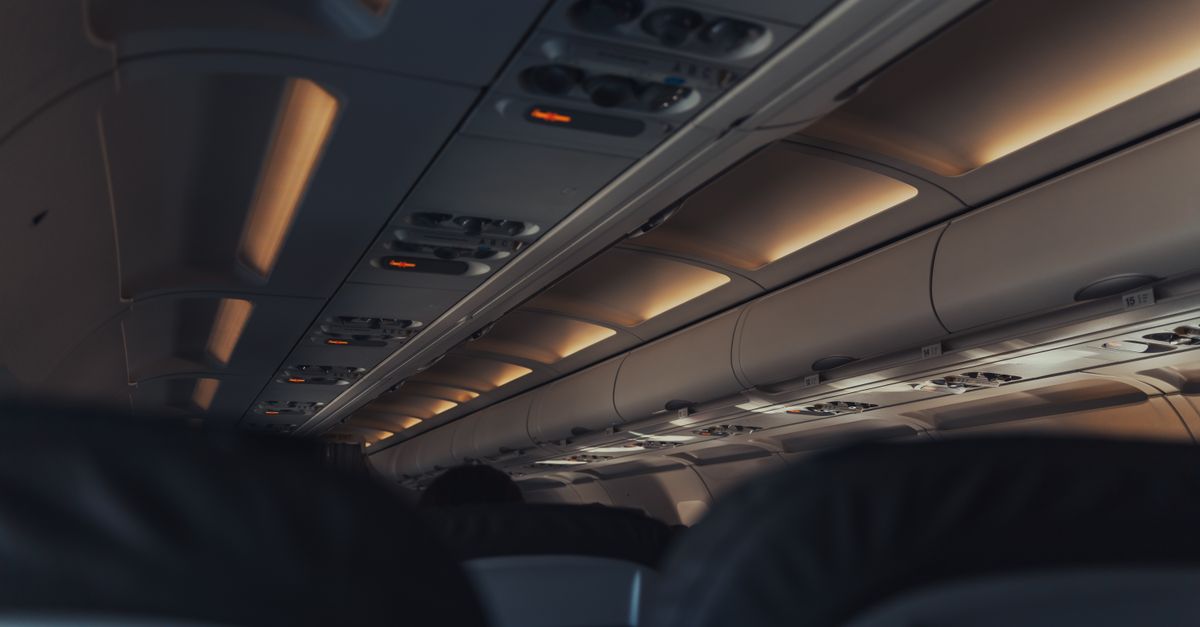 Interior view of a commercial airplane cabin focusing on overhead lights and seats.