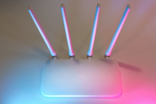 Sleek white wireless router with four antennas emitting soft blue and pink light.