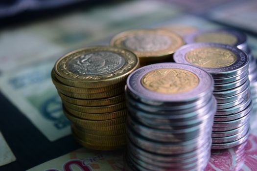 Close-up of stacked gold and silver coins on various currency notes, symbolizing wealth and savings.