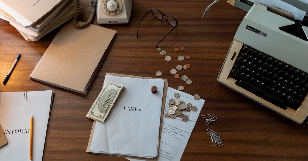 Vintage workspace with typewriter, documents, and telephone on a wooden desk, evoking a classic office setting.