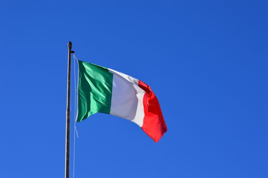 Italian flag flying against a vibrant blue sky, symbolizing national pride and identity.