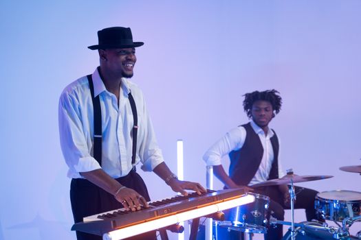Two musicians playing keyboard and drums in a modern, stylish setting.