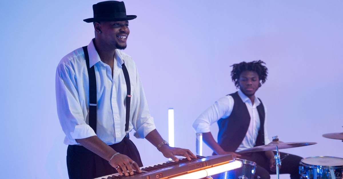 Two musicians playing keyboard and drums in a modern, stylish setting.