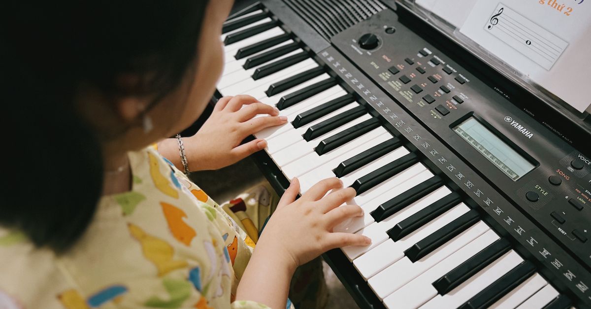 A young child practicing music on a digital keyboard indoors.