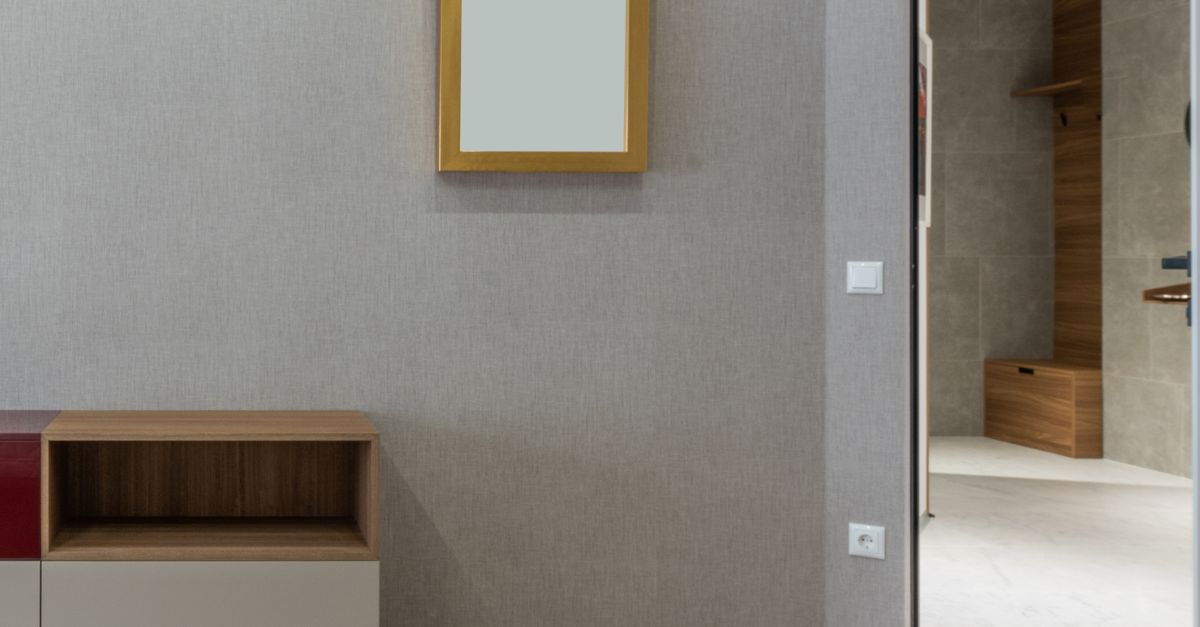 Spacious contemporary new apartment room with empty shelves and rectangular mirror on gray walls