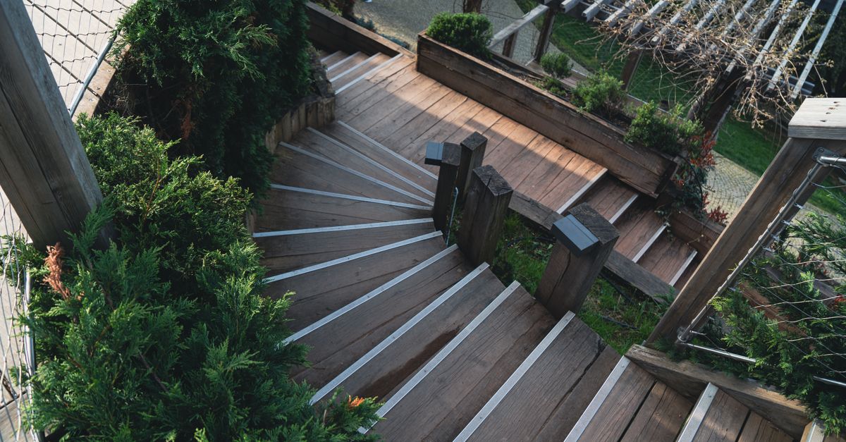 Explore the elegance of a wooden staircase surrounded by lush greenery in an outdoor garden.