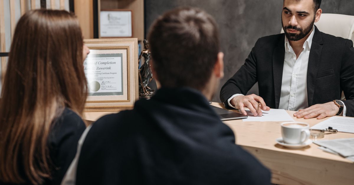 A lawyer in an elegant office meeting with clients, discussing documents.