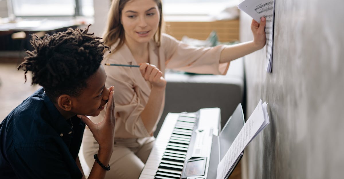 A piano teacher instructs a young student at the keyboard, focusing on music sheets.