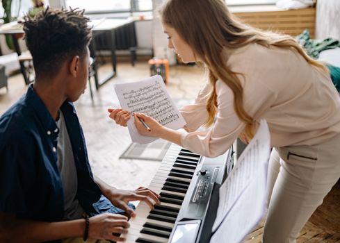 A teacher helps a student understand musical notes during a piano lesson.