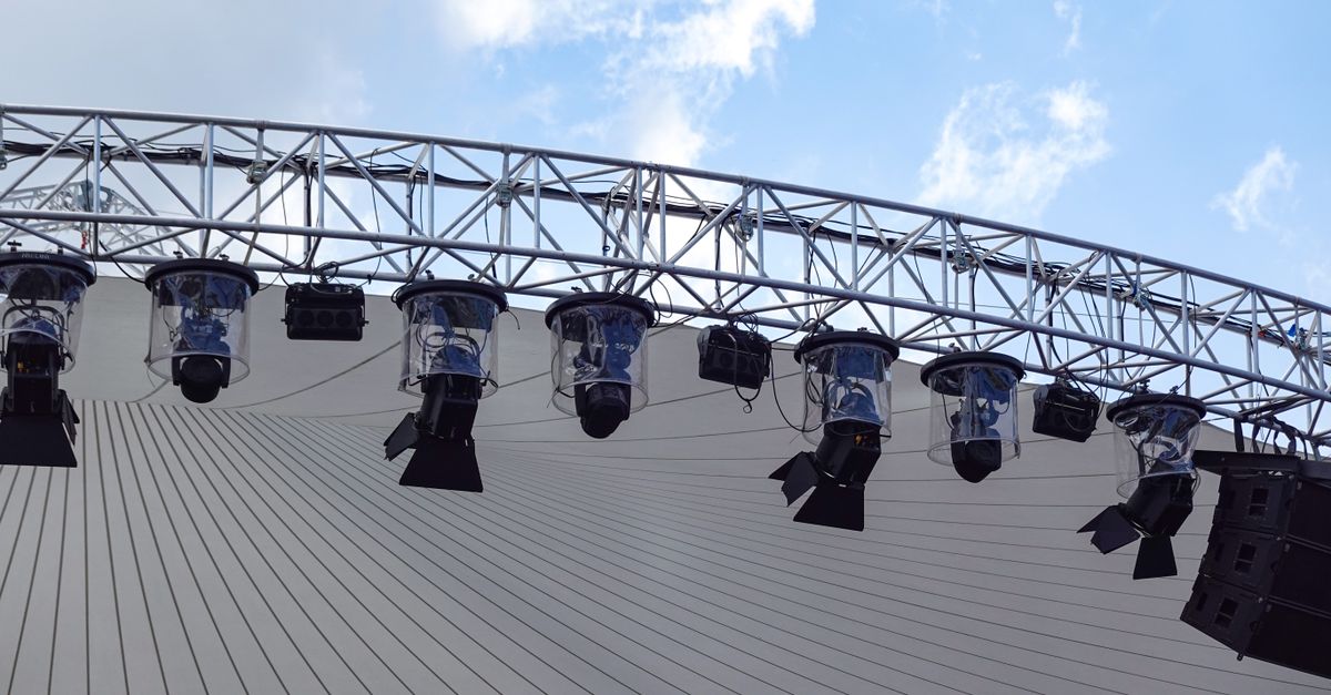 Overhead view of an outdoor stage with modern lighting setup against a blue sky.