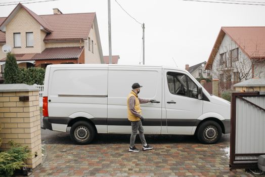 A delivery man exits his van in a suburban residential neighborhood for home delivery.