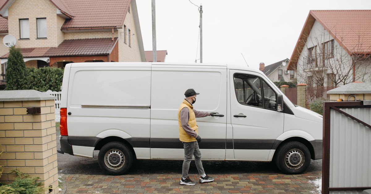 A delivery man exits his van in a suburban residential neighborhood for home delivery.