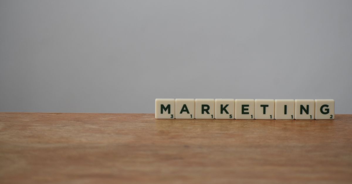 Scrabble tiles spelling 'MARKETING' on a wooden table with a neutral background.