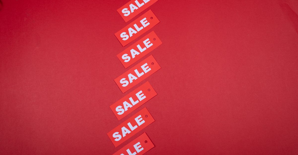 Top view of red sale tags arranged on a vibrant red background for commercial use.