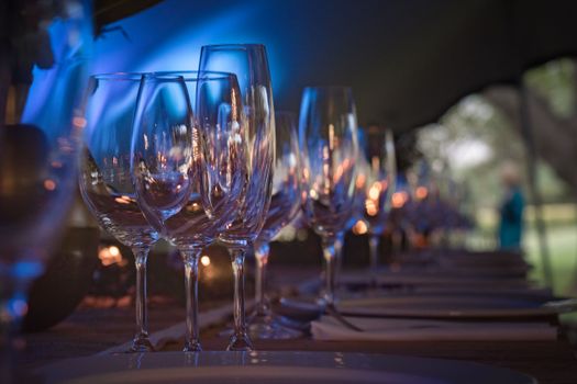 A row of sparkling crystal glasses on a dimly lit event table setting.