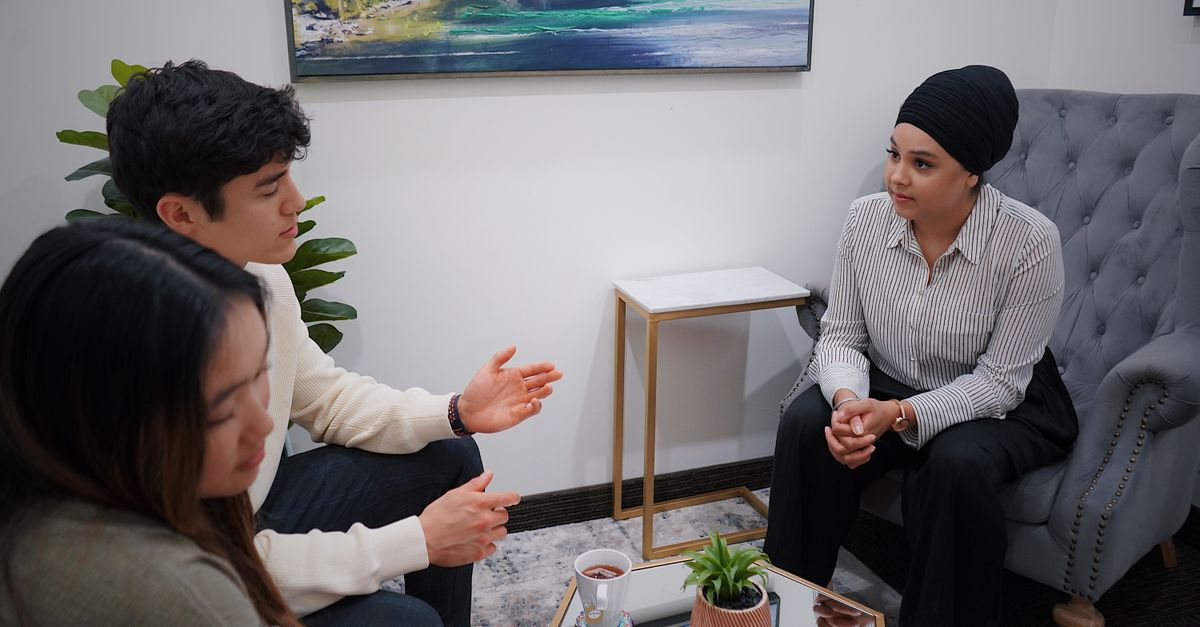 A couple in a therapy session discussing issues with a therapist in a modern office.