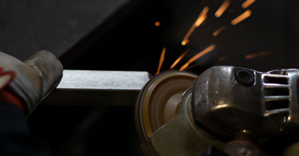 Angle grinder working on steel, emitting bright sparks. Industrial close-up shot.