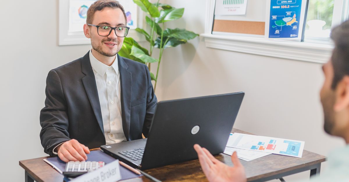 A mortgage broker and client discussing loan options in a modern office setting.