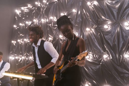 Energetic live performance by a band featuring electric guitar and keyboard players under creative lighting.