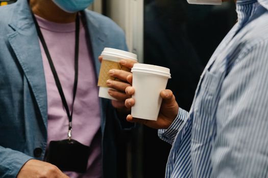 Two professionals holding coffee cups during a casual meeting indoors.