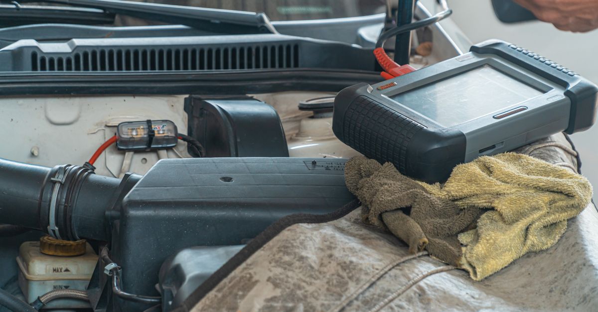 Close-up of a car engine inspection using a diagnostic tool in a garage setting, showcasing automotive maintenance and repair.