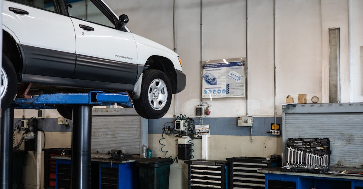 A car is elevated on a lift in a modern automotive repair shop, showcasing tools and equipment.