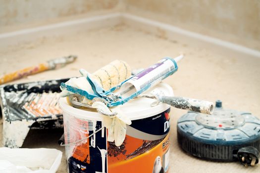 A collection of painting tools and materials for home renovation, featuring paint rollers and a bucket.
