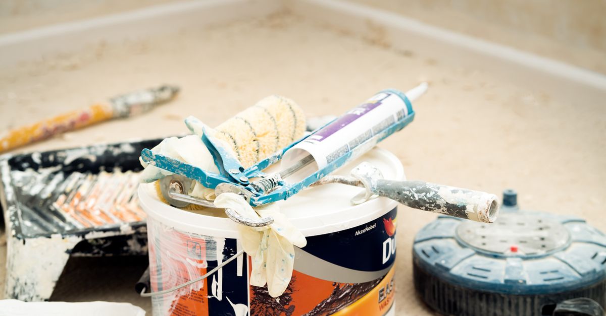 A collection of painting tools and materials for home renovation, featuring paint rollers and a bucket.